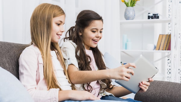 Kid playing mobile game while she is doing homework