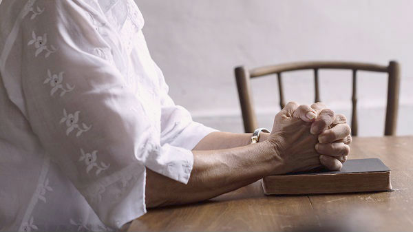 hand praying on bible book