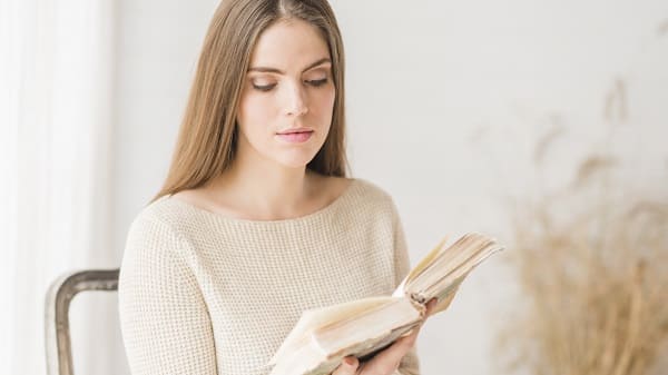 Blonde young woman sitting on chair reading book