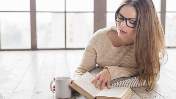 blonde young woman lying hardwood floor reading book